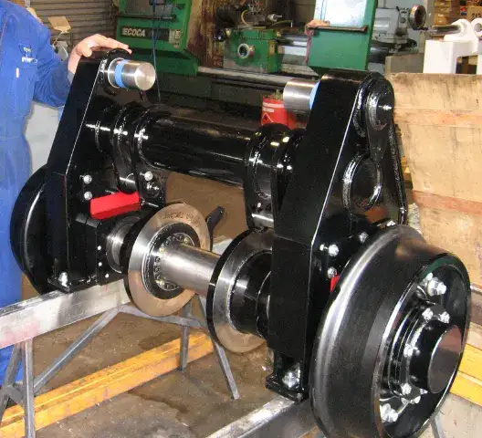 Custom-built railway chassis and wheelset, freshly painted black, in a fabrication workshop.